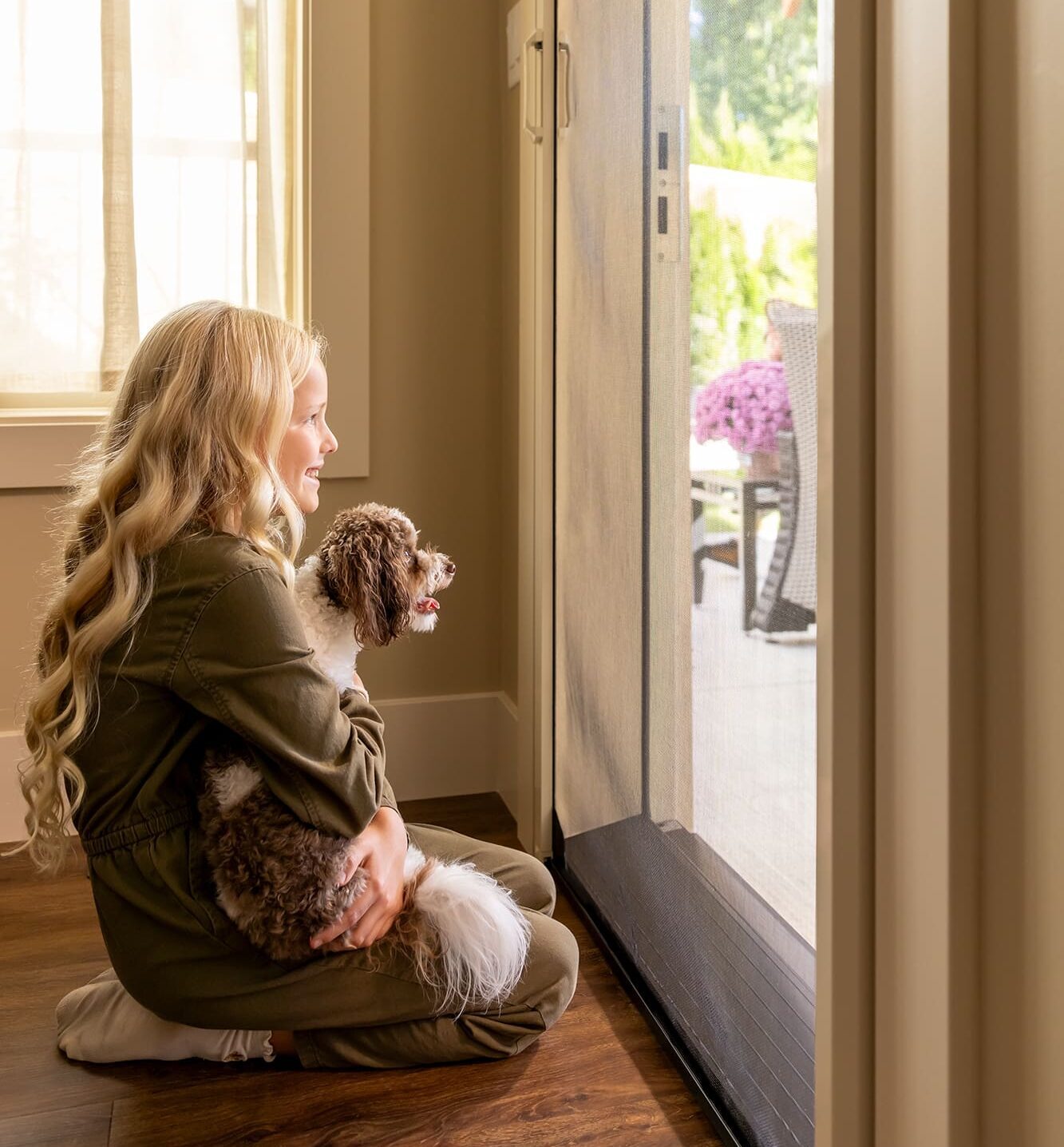 Girl and her dog looking outside through Phantom Screens' door screen with mesh lock.